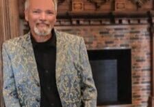 A man in a suit standing next to a fireplace.